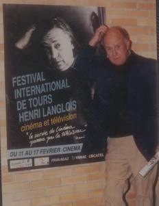 Jean Rouch pose à côté de l'affiche du festival